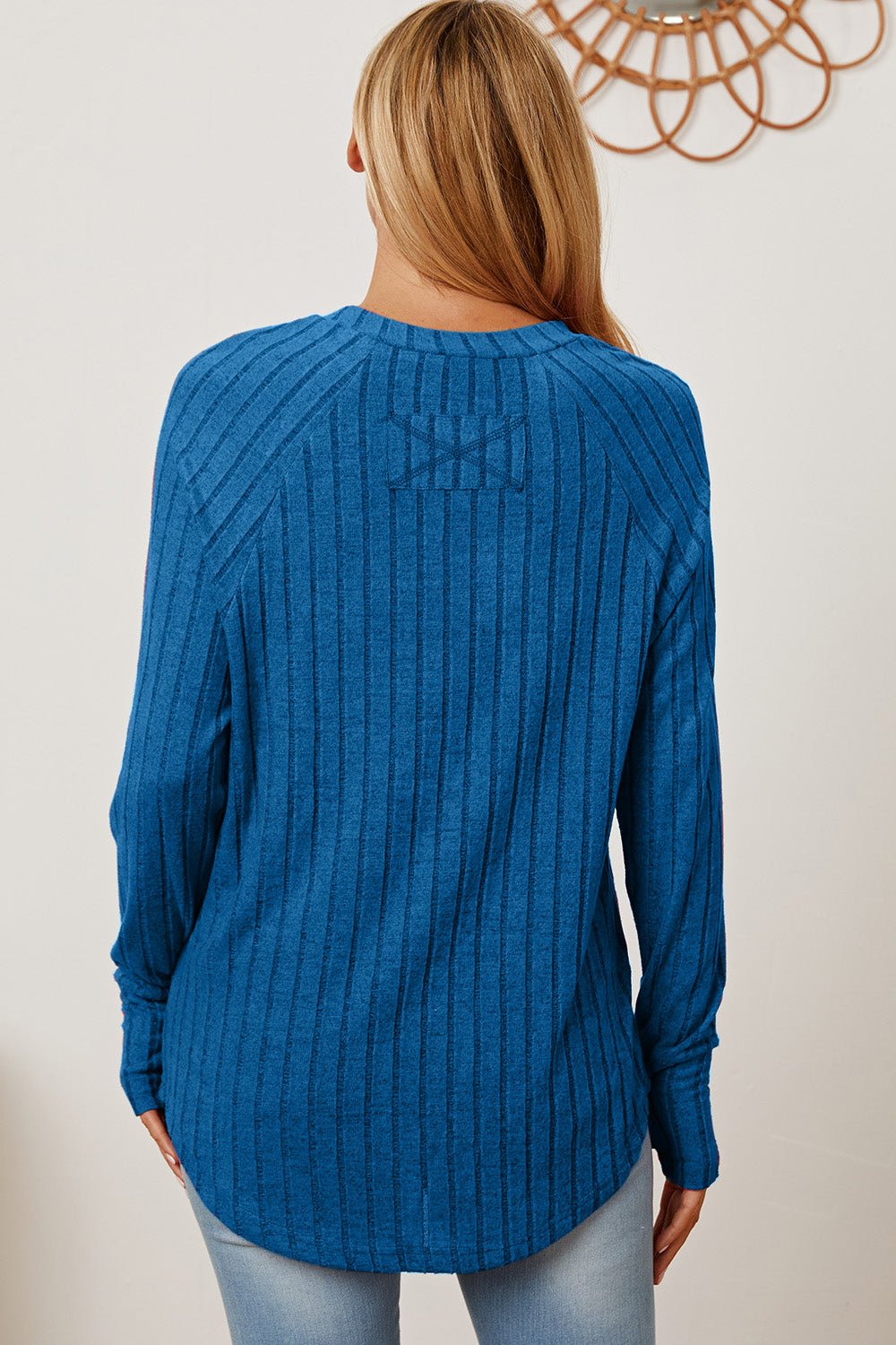 Woman wearing blue ribbed thumbhole sleeve t-shirt, back view