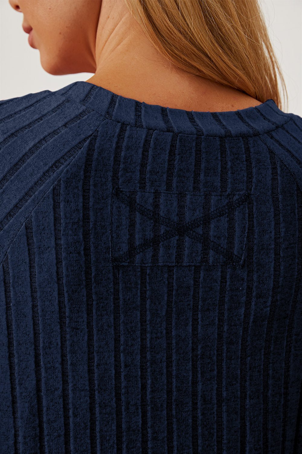 Close-up of a navy ribbed t-shirt with thumbhole sleeves, showcasing the back detail and texture.