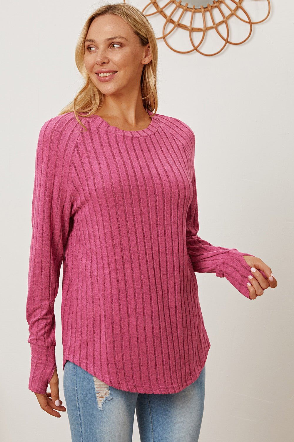 Woman wearing pink ribbed thumbhole sleeve T-shirt, basic style, paired with jeans.