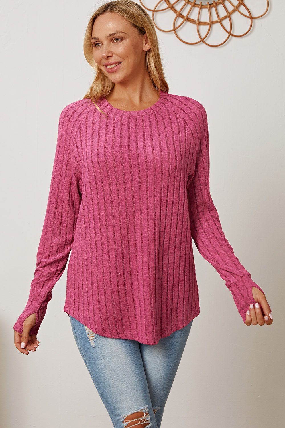 Pink ribbed thumbhole sleeve t-shirt styled with ripped jeans, featuring a casual and comfortable look.