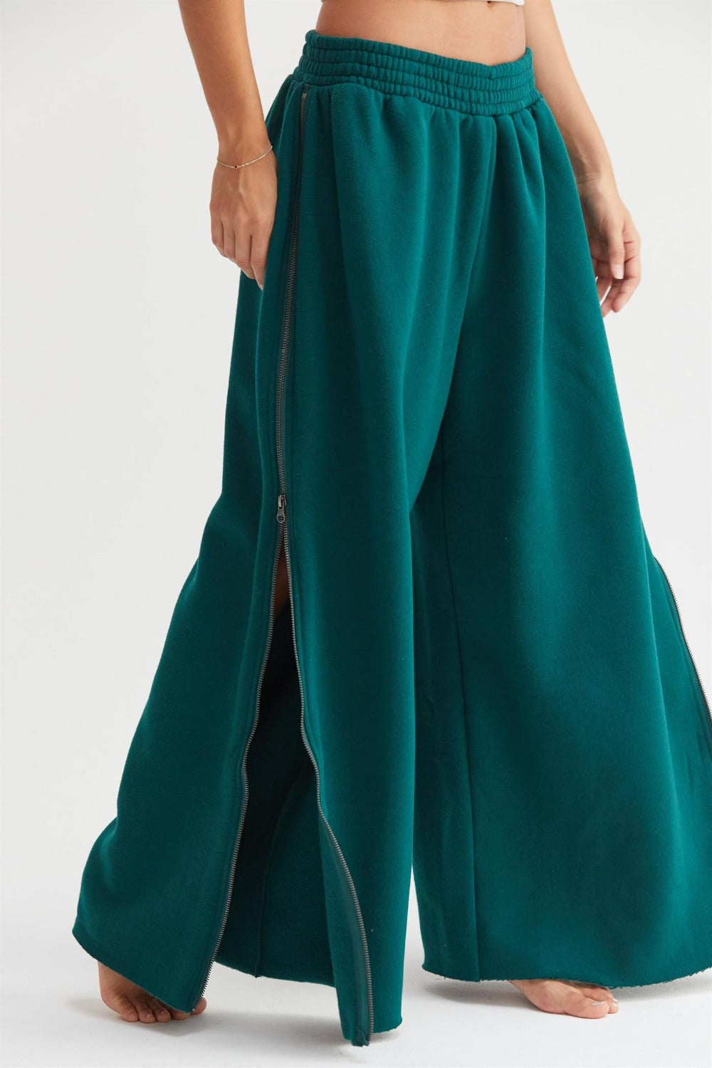 Dark green wide-leg sweatpants with side zippers, featuring an elastic waist for comfort and mobility.