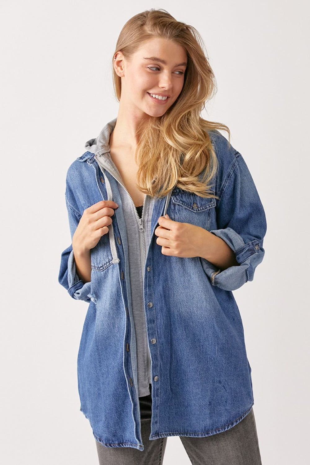 Woman wearing a zip up hooded denim shirt with washed finish and pockets, highlighting its slightly stretchy 100% cotton fabric.